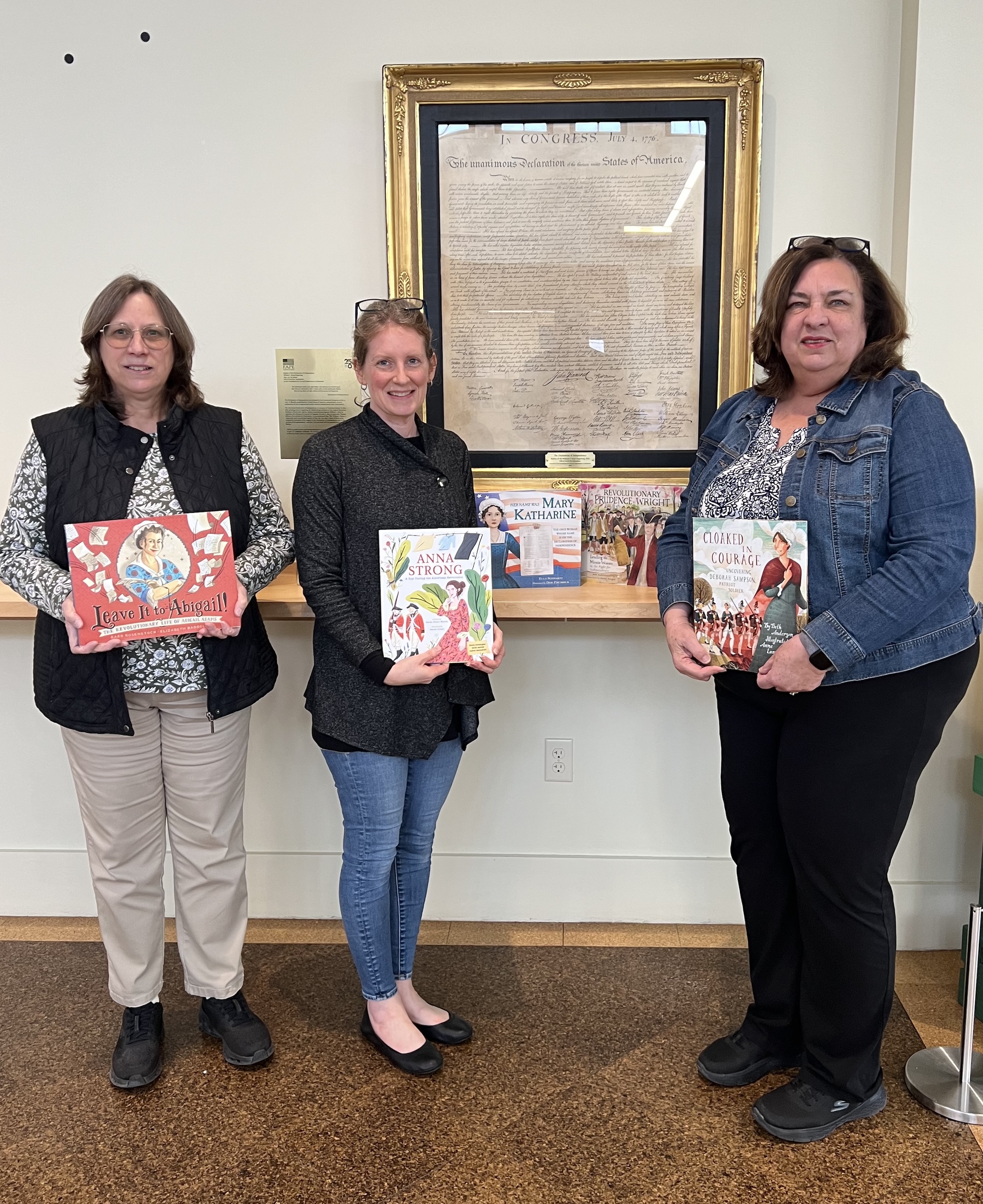 Members holding books donated to the Tiverton Library